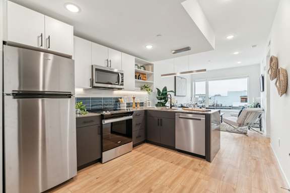 A modern kitchen with a stainless steel refrigerator and wooden flooring.