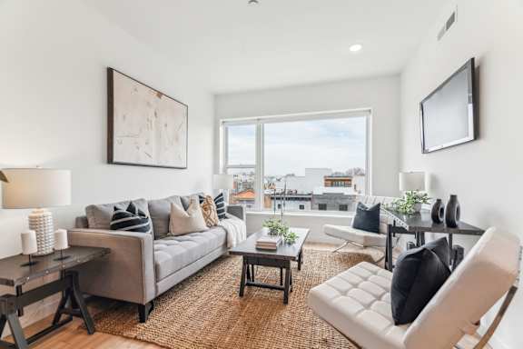 A modern living room with a grey sofa, a black and white chair, and a painting on the wall.