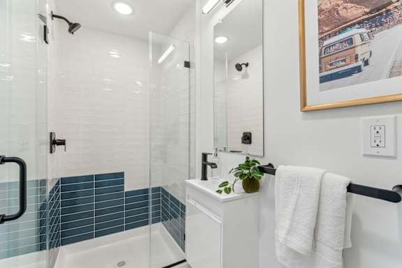 A white bathroom with a blue tiled shower.