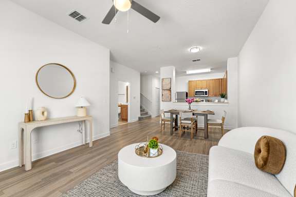 Kissimmee, FL Townhomes for Rent - Estates at Lake Cecile – A modern living room with a white couch and a round mirror on the wall.