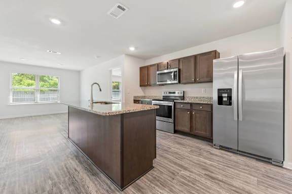 A modern kitchen with a refrigerator, microwave, and oven.