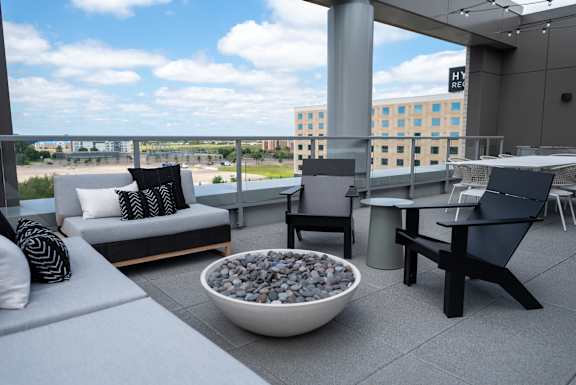 A patio with a couch, chairs, and a bowl of rocks.