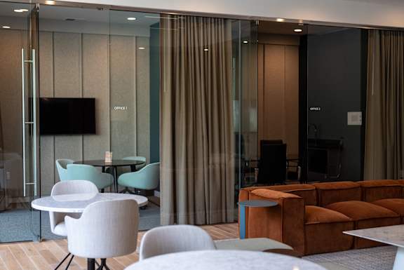 A modern living room with a glass wall and a television.