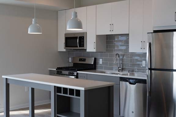 A modern kitchen with a stainless steel refrigerator, microwave, and dishwasher.