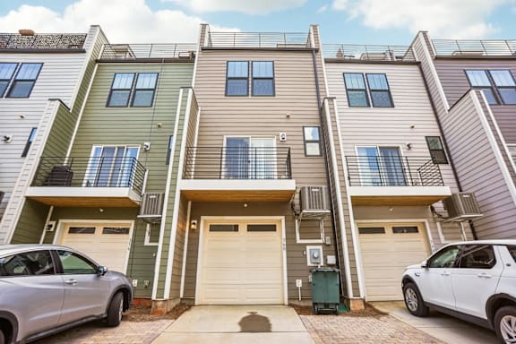Two cars are parked in front of a two-story apartment building.