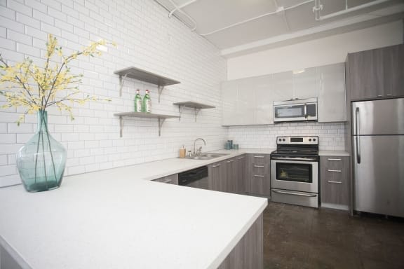 a kitchen with a white counter top and a stainless steel refrigerator