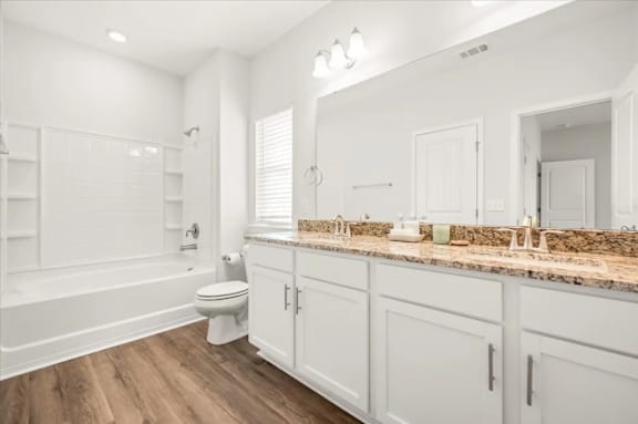 A white bathroom with a toilet, sink, and cabinets.