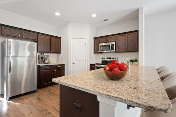 A kitchen with a granite countertop and a refrigerator.