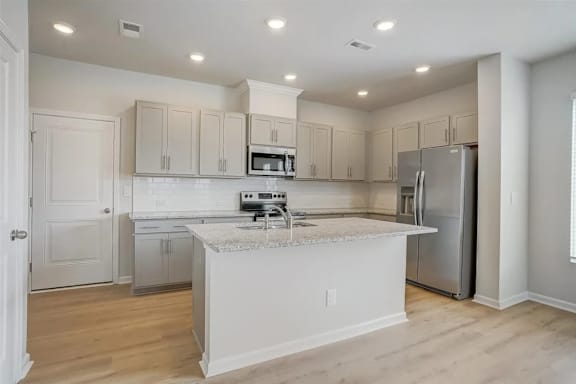 A kitchen with a white island and stainless steel appliances.