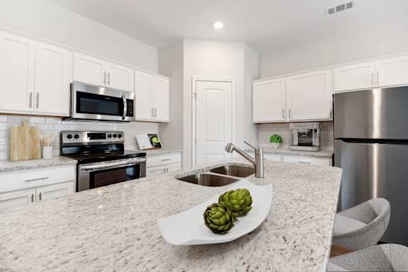 A kitchen with a marble countertop and stainless steel appliances.