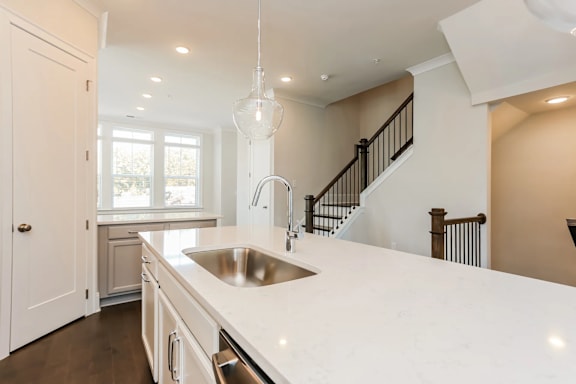 A modern kitchen with a white countertop and a stainless steel sink.