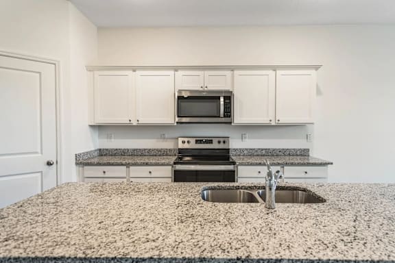 A kitchen with granite countertops and white cabinets.