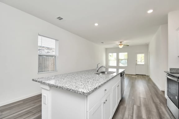A kitchen with white cabinets and a granite countertop.
