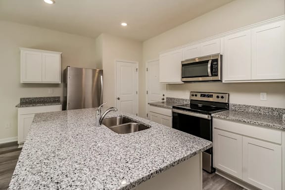 A kitchen with granite countertops and white cabinets.