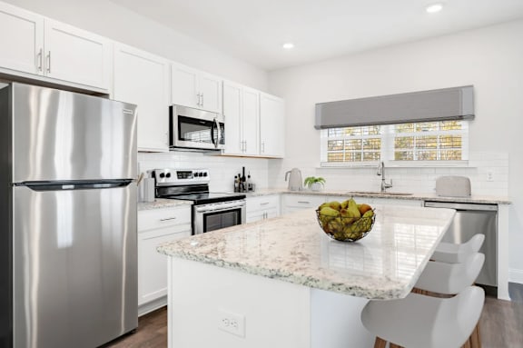 A modern kitchen with a granite countertop and stainless steel appliances.
