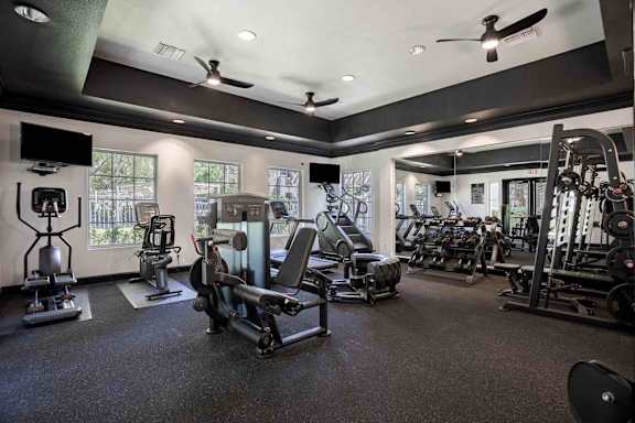 A spacious gym with a variety of equipment including treadmills, stationary bikes, and weight machines.