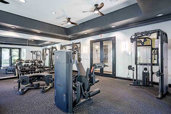 A gym with a variety of equipment including a weight machine, a bench press, and a squat rack.