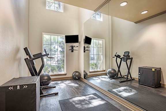 A home gym with a variety of equipment including a treadmill, weights, and a television.