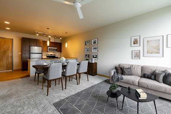 A modern living room with a dining table and grey couch.