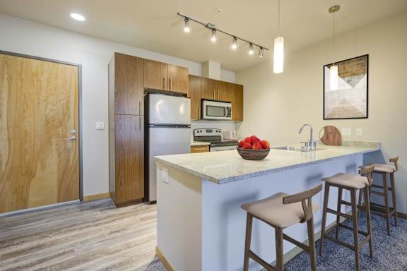 A kitchen with a white counter top and wooden bar stools.