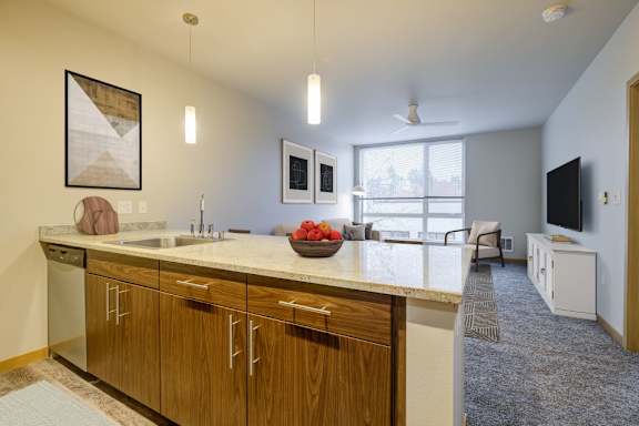 A kitchen with wooden cabinets and a countertop with a bowl of fruit on it.