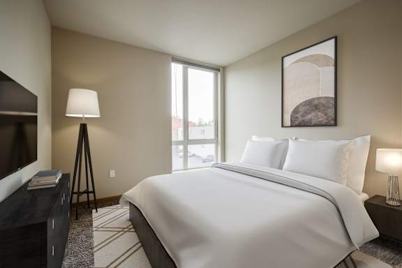 A bedroom with a large bed, a television, and a painting on the wall.