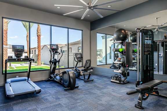 A gym with a variety of equipment including treadmills, weights, and exercise balls.