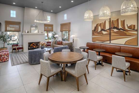 A living room with a fireplace, a dining table, and a large painting on the wall.