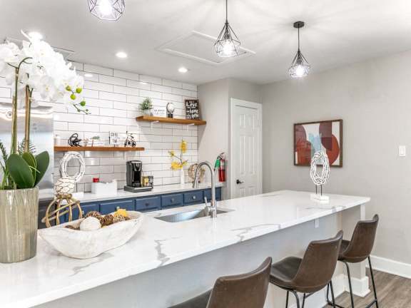 A kitchen with a white countertop and brown chairs.