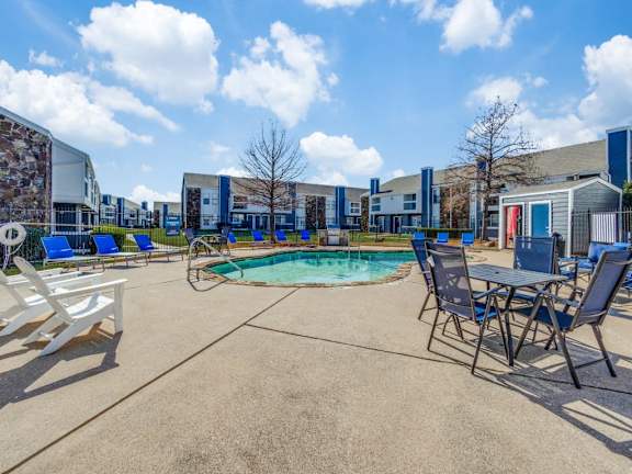 A pool area with chairs and a table in front of a building.