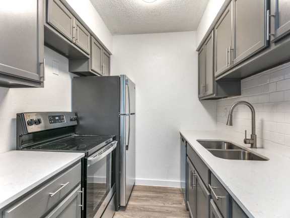 A kitchen with a stove, refrigerator, and sink.