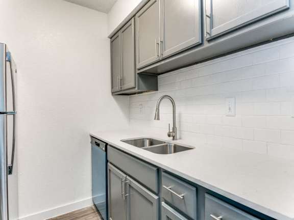 A kitchen with a sink and a refrigerator.
