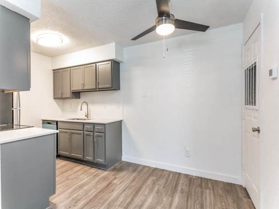 A kitchen with a ceiling fan and wooden floors.