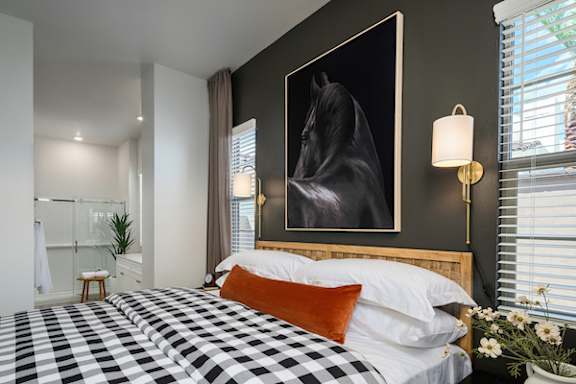 A bedroom with a large bed and a painting of a horse on the wall.