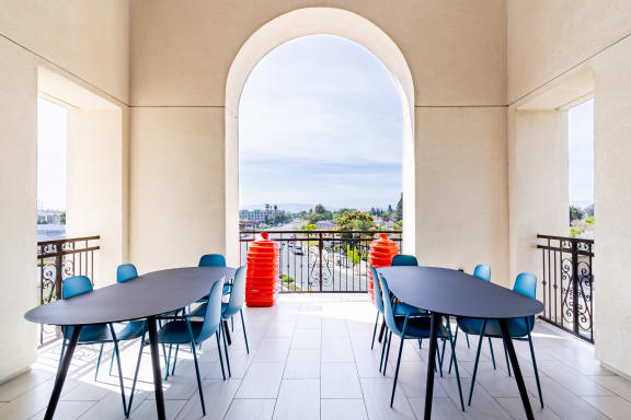 a dining area with tables and chairs and a balcony with a view of the city