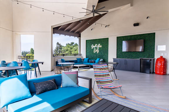a patio with blue couches and chairs and tables and a tv