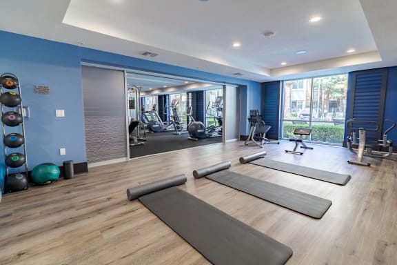 a gym with yoga mats and exercise equipment on a wood floor