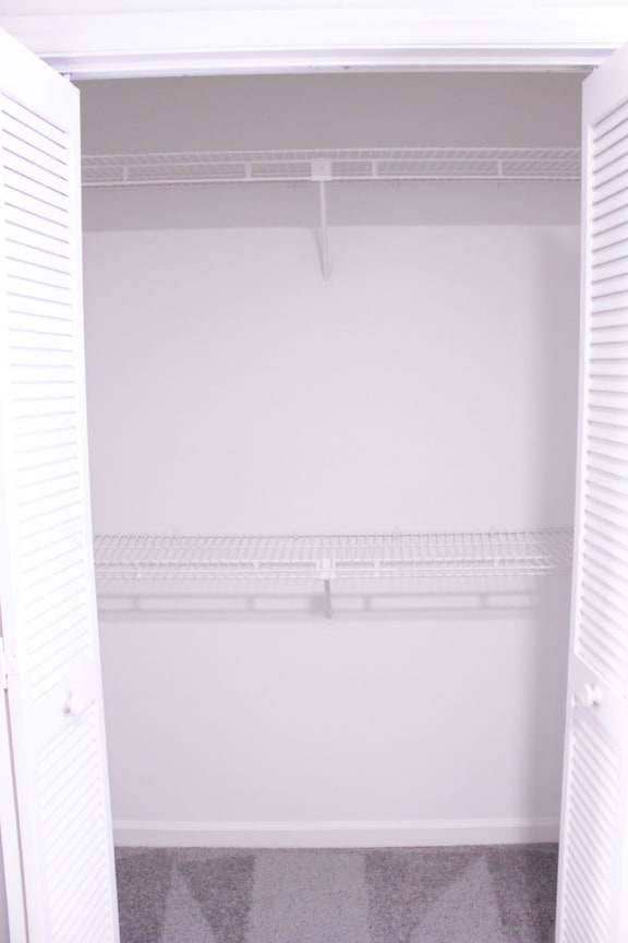 an empty closet in a white room with white shutters