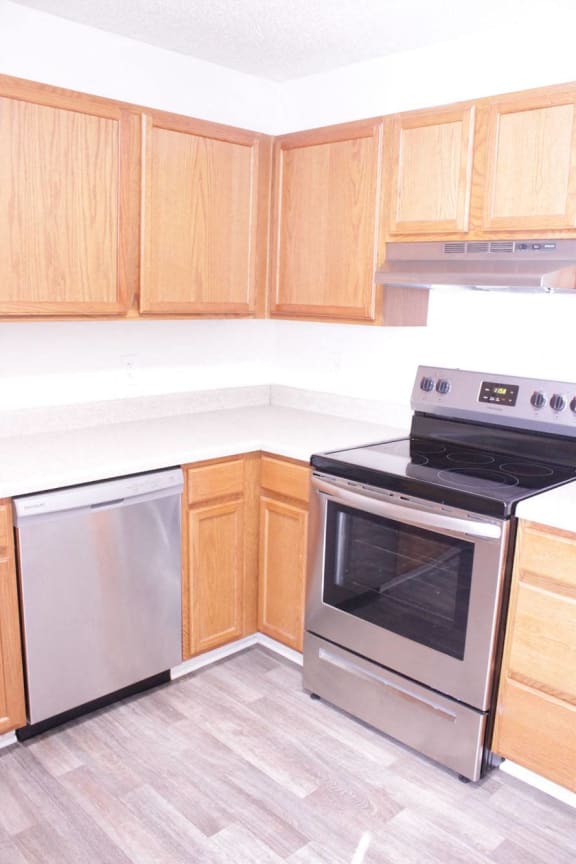 an empty kitchen with wood cabinets and stainless steel appliances