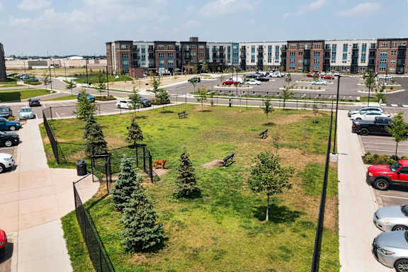 A parking lot with cars and a green space in front of a building.
