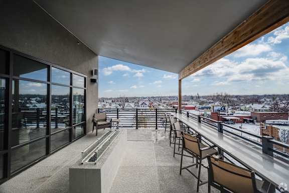 A balcony with chairs and a table overlooking a snowy landscape.