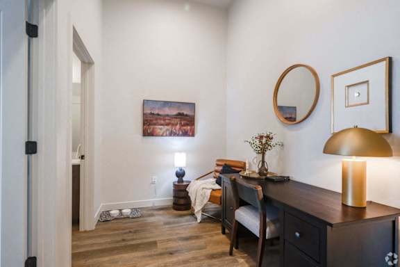 A room with a painting on the wall and a lamp on the desk.