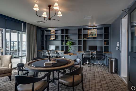 A room with a round table and chairs, a book on the table, and a plant on the shelf.