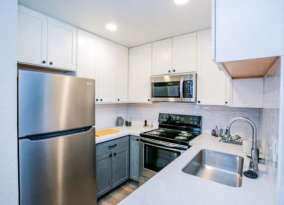 A modern kitchen with a stainless steel refrigerator and a stove top oven.