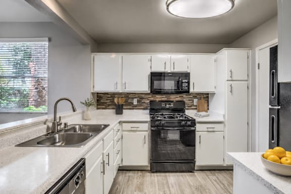 A modern kitchen with white cabinets and a black stove top oven.