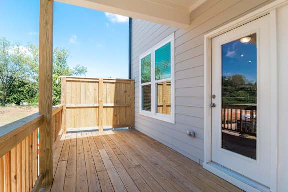 A wooden deck with a white door and a window.