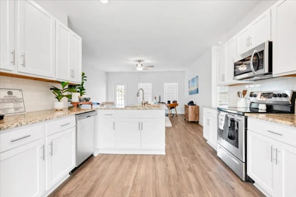 A kitchen with white cabinets and a wooden floor.
