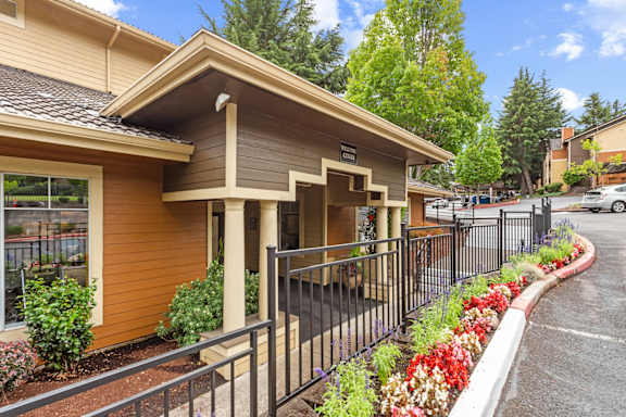 A small building with a brown and tan exterior and a black fence in front at MonteVista Apartments, Beaverton, Oregon