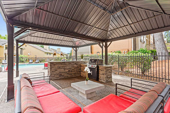 A patio with red cushioned seating and a fireplace under a metal roof at MonteVista Apartments, Oregon