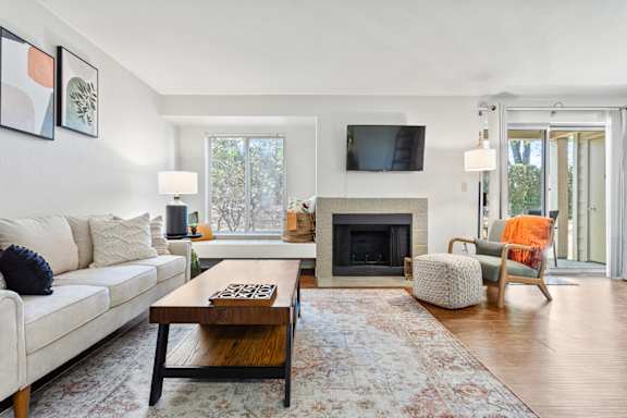 A living room with a white couch, a coffee table, a fireplace, and a television.